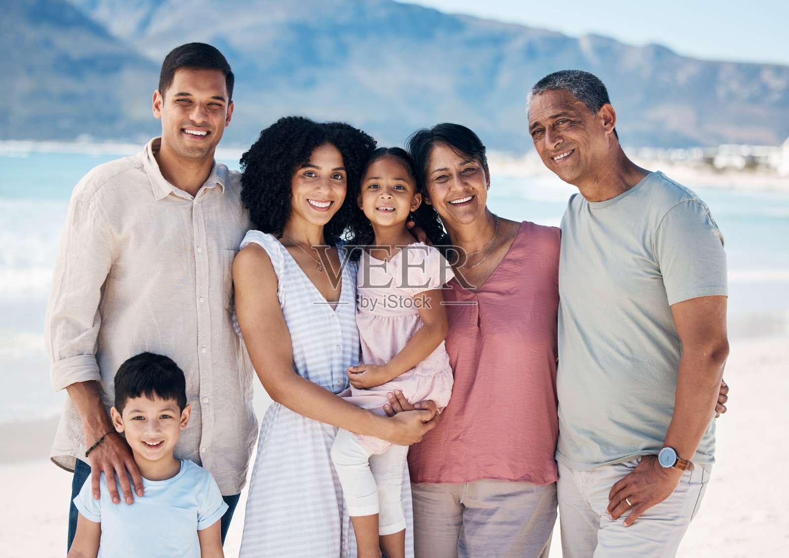 祖父母，孩子和父母在海滩上，为微笑拍照或散步，在度假时照顾或建立关系。带着孩子的妈妈、爸爸和长辈，自由或爱在大家庭中度假、出海或避暑照片摄影图片
