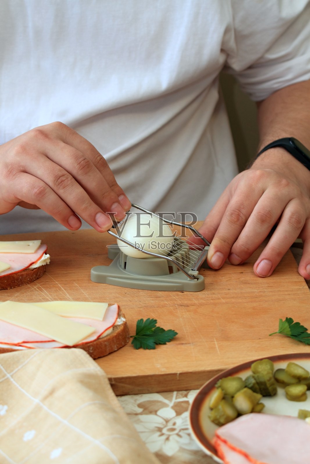 厨师的手用切蛋器切煮熟的鸡蛋照片摄影图片