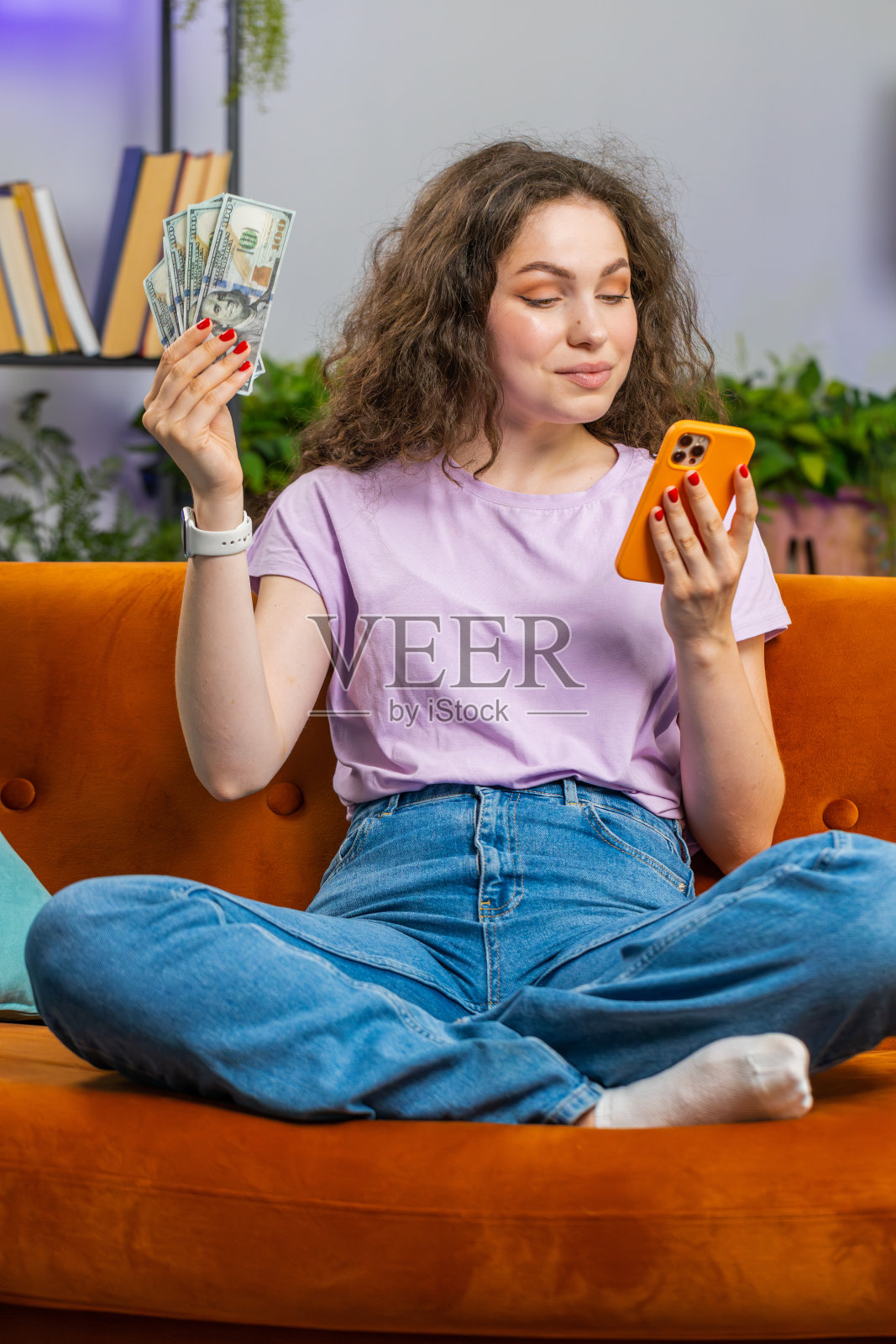 微笑快乐的年轻女子用智能手机计算现金收入节省了家里的彩票中奖预算照片摄影图片