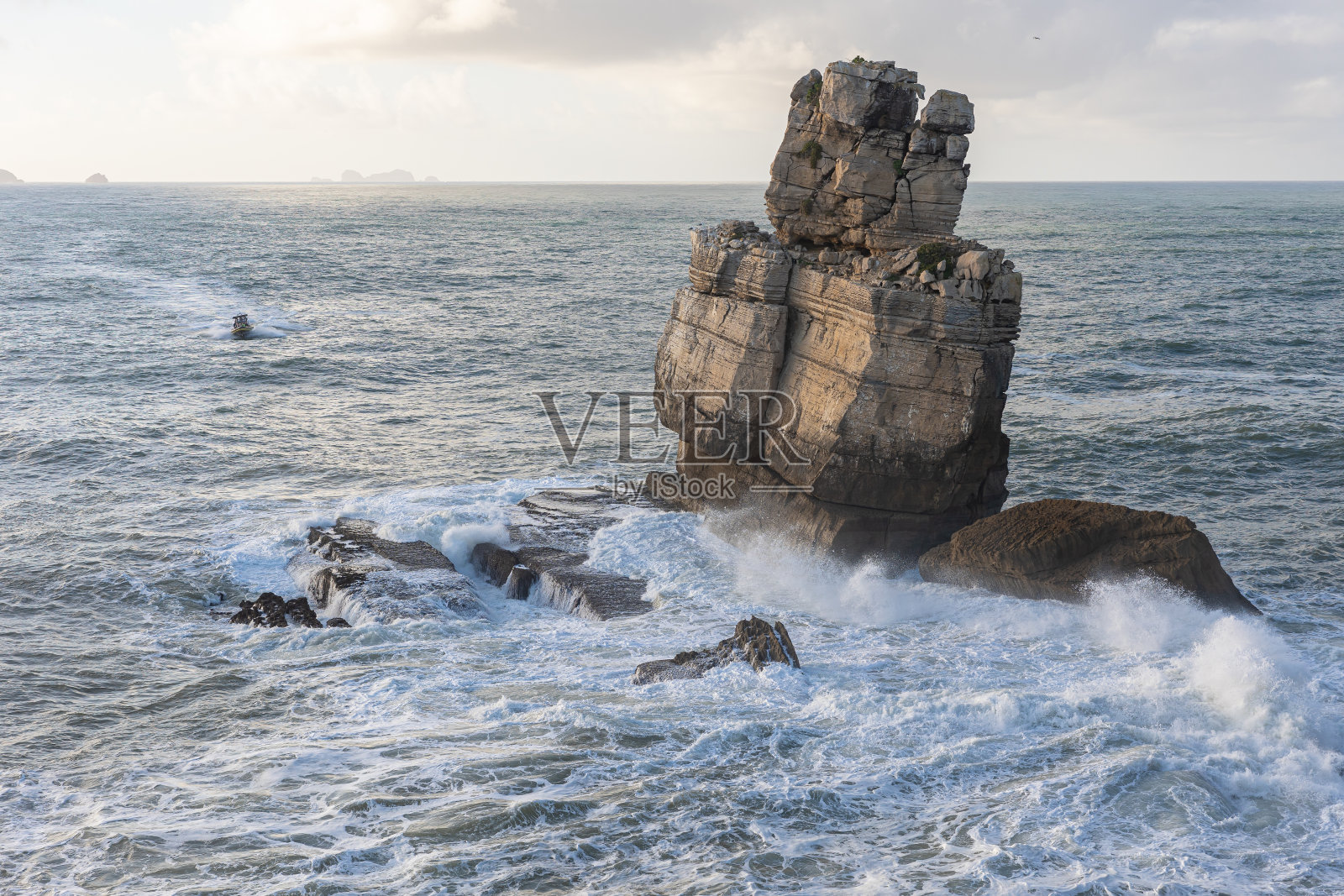大海中间的大石山和小船——景观照片摄影图片