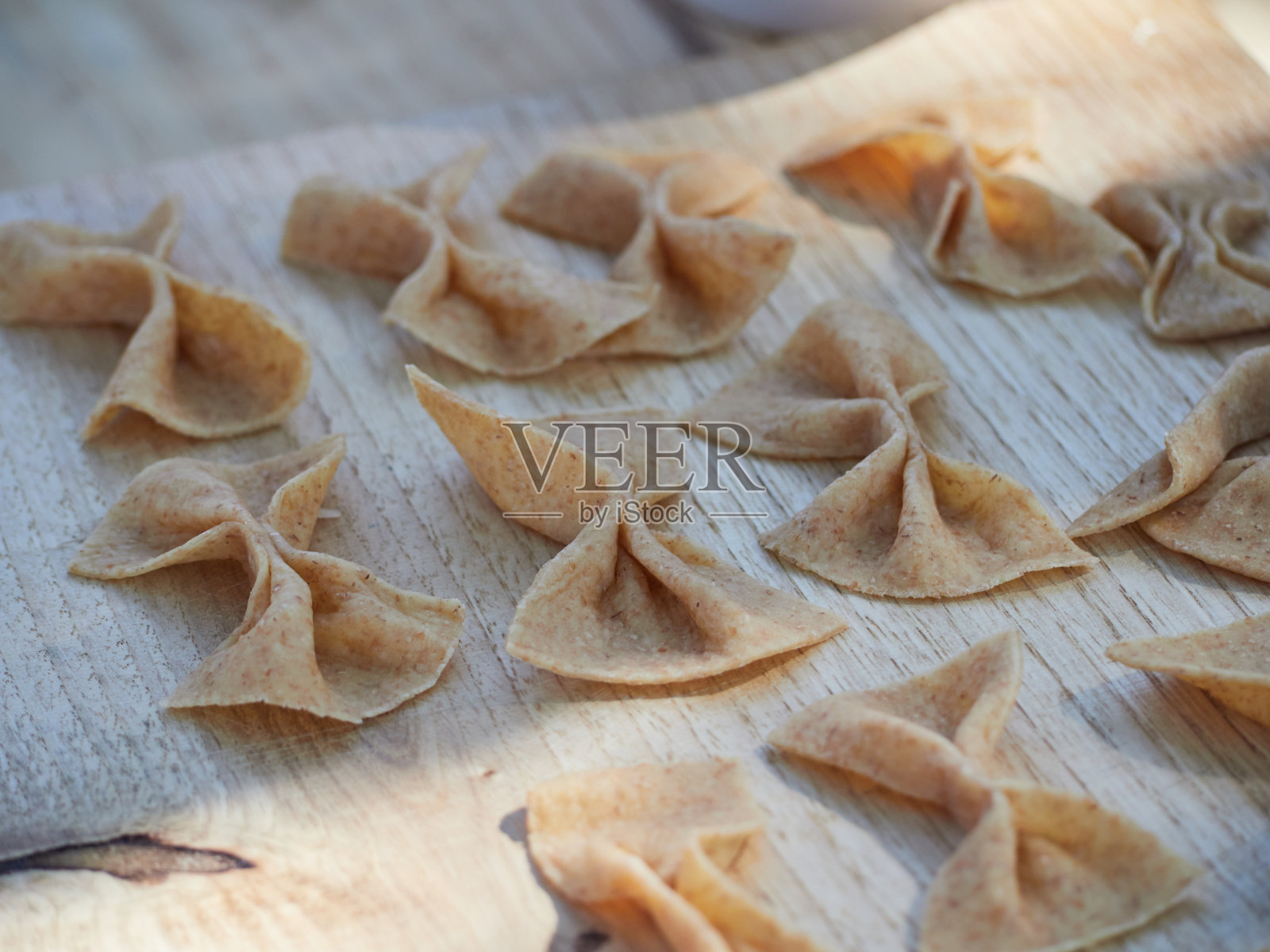 新鲜的、生的、自制的全谷意大利面，做成弓的形状，放在木板上照片摄影图片