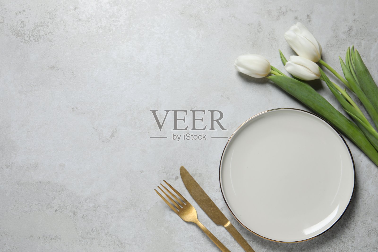 时尚的餐桌设置与餐具和鲜花在灰色背景，平铺。文本空间照片摄影图片