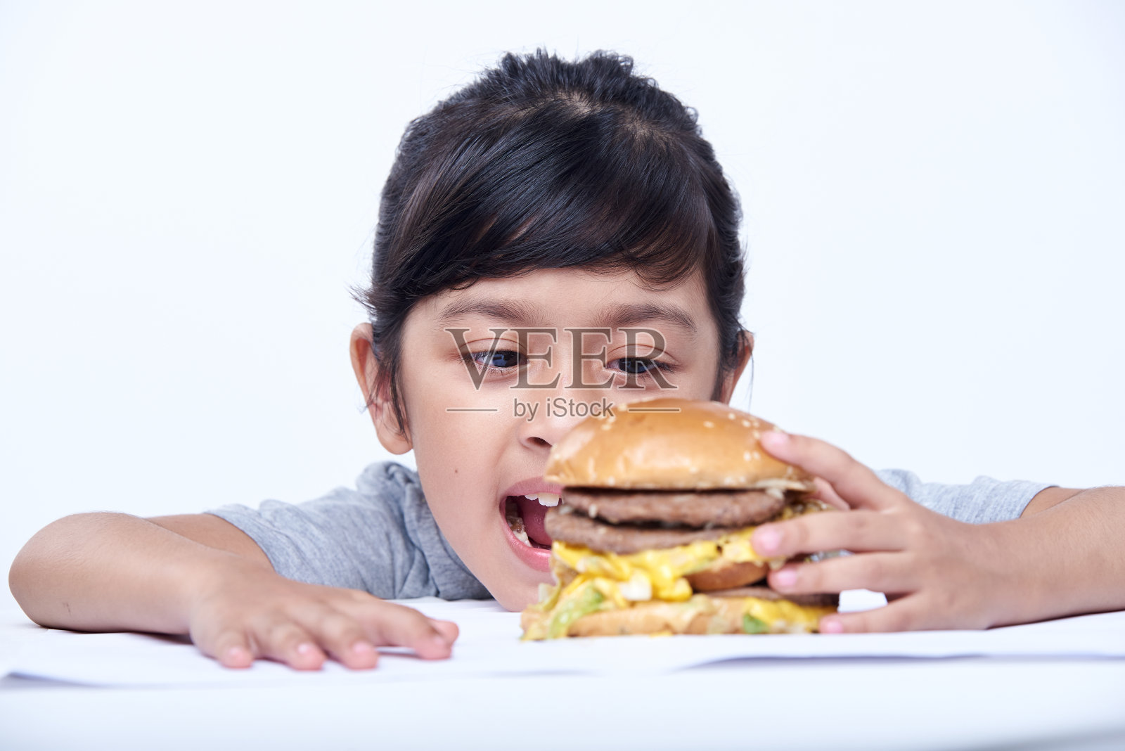 饥饿的小女孩正在享用汉堡包快餐照片摄影图片