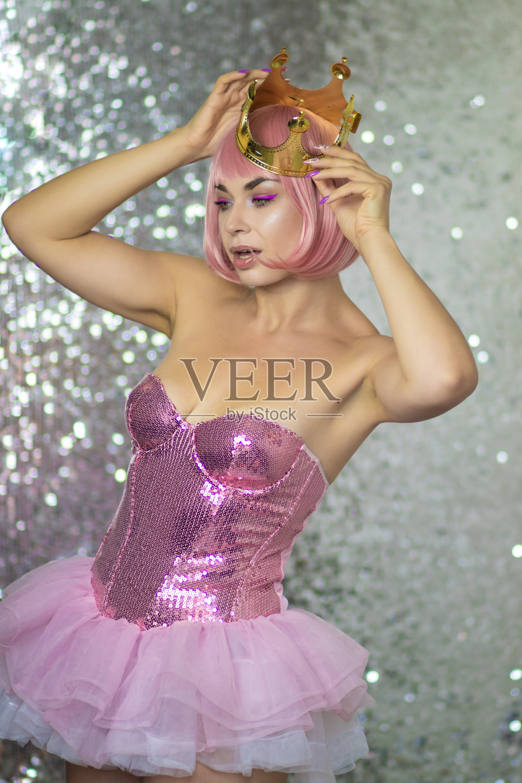 戴着金色皇冠的粉色假发的女人。万圣节照片摄影图片