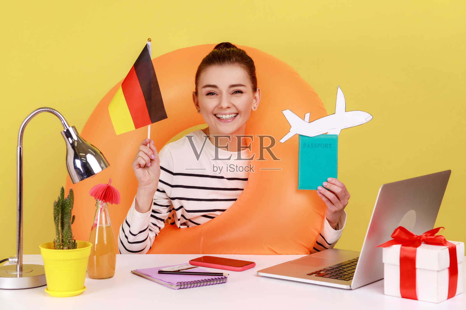 戴着橡胶圈的女经理拿着护照和德国国旗，很高兴能去德国旅行。照片摄影图片