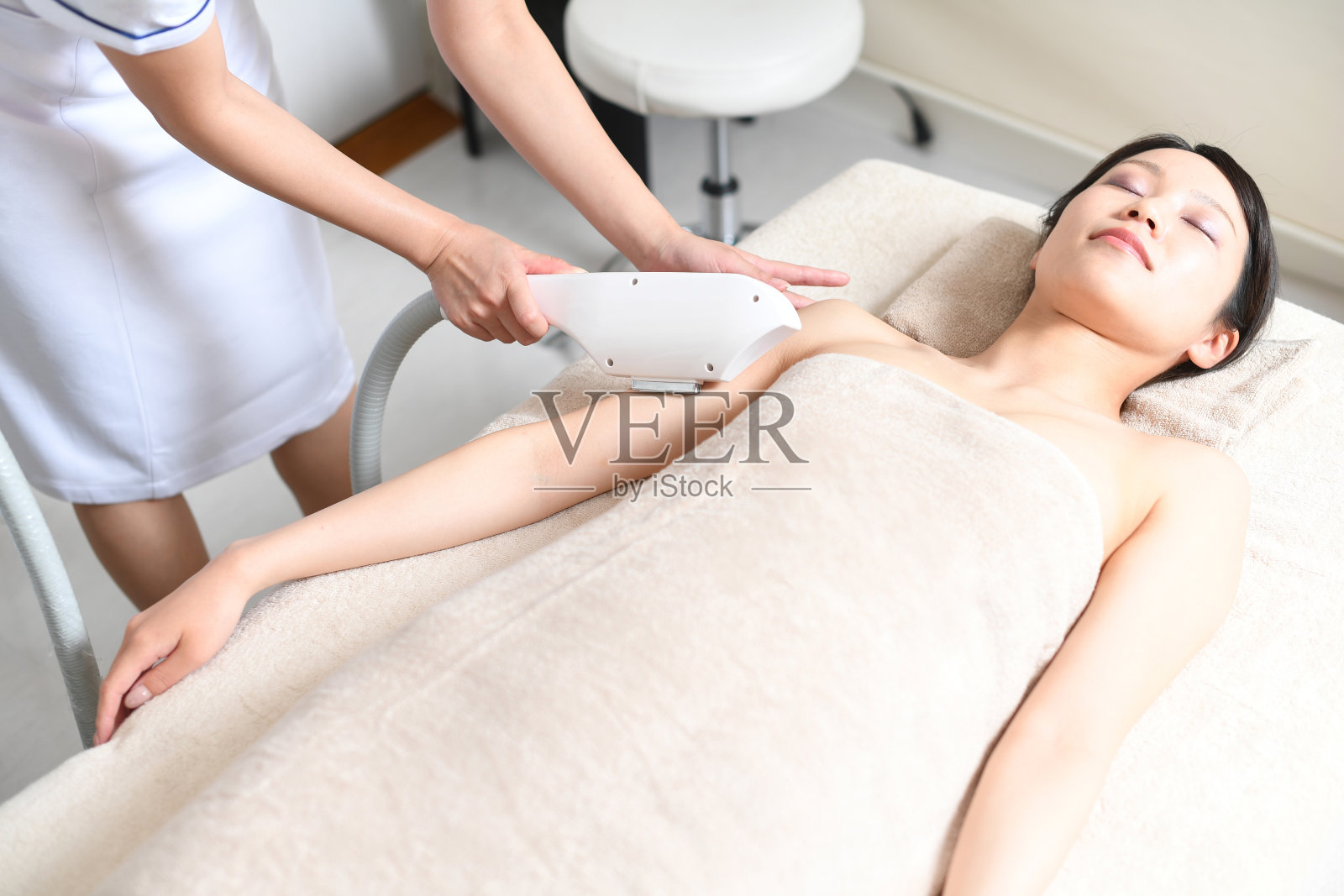 年轻的亚洲妇女正在接受上臂激光脱毛治疗照片摄影图片