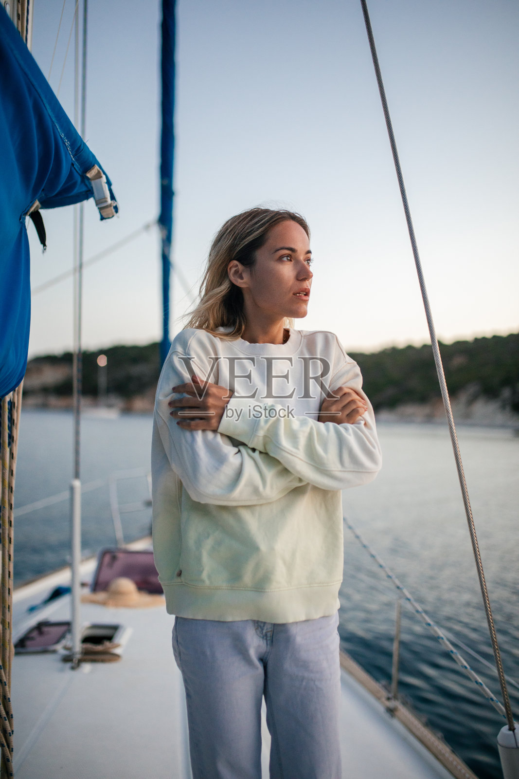 美丽的女人站在帆船上，在秋天的淡季假期的早晨或晚上感到寒冷照片摄影图片