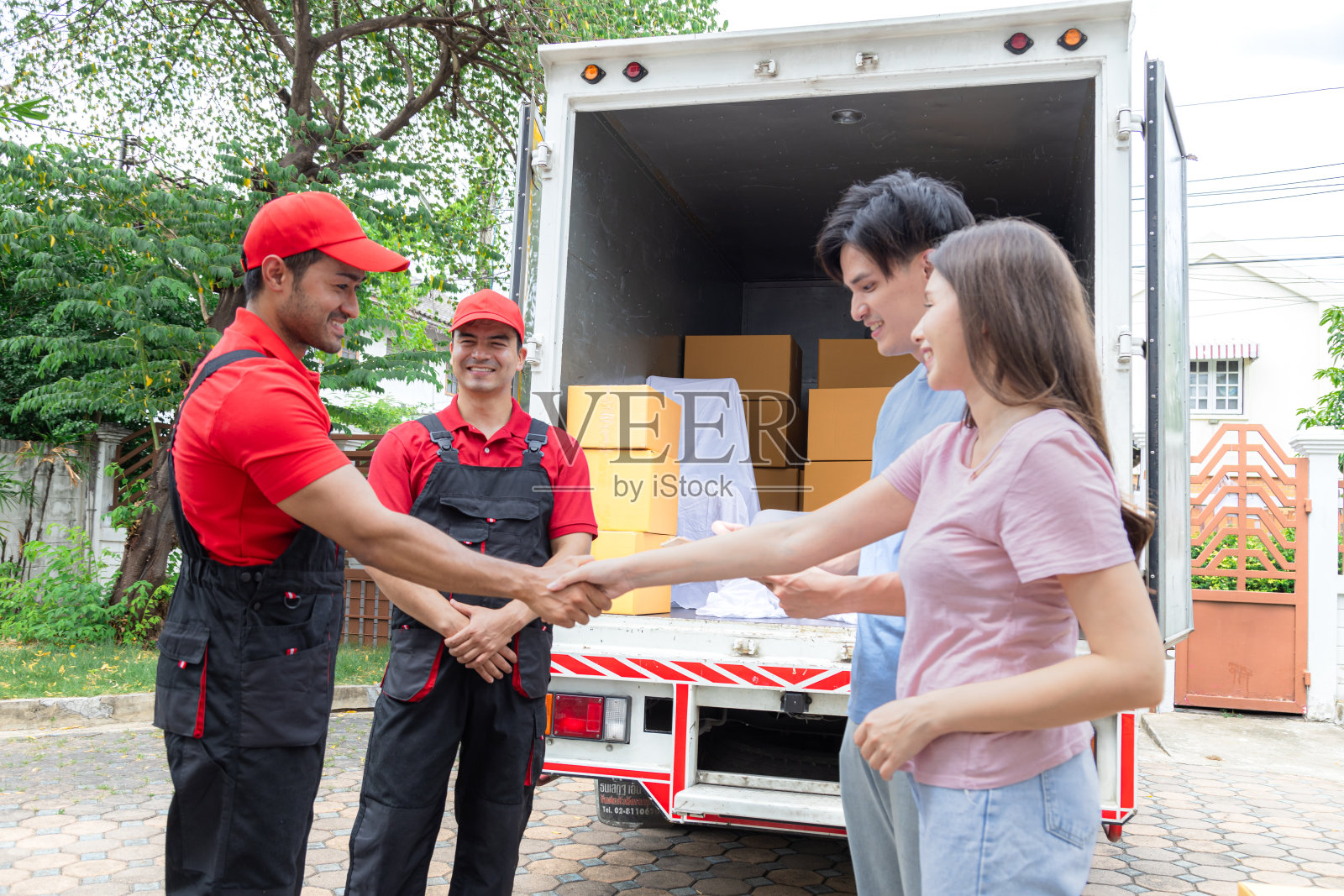 亚洲夫妇新婚满意的签署交付清单与专业服务物流搬家员工在搬运或搬运家具后，印度和高加索团队合作伙伴关系照片摄影图片