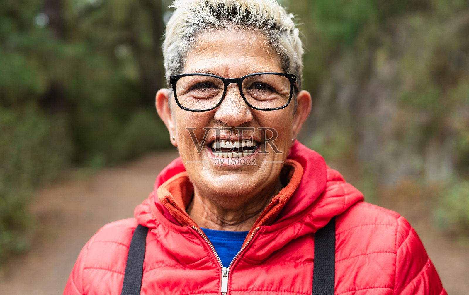 快乐的老年妇女在森林徒步活动期间享受乐趣-冒险和旅行的人的概念照片摄影图片