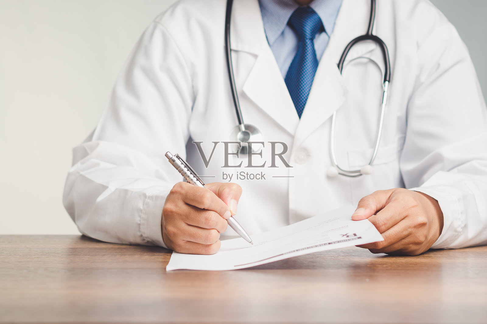 医生坐在医院里，手里拿着笔，在药方上写字照片摄影图片