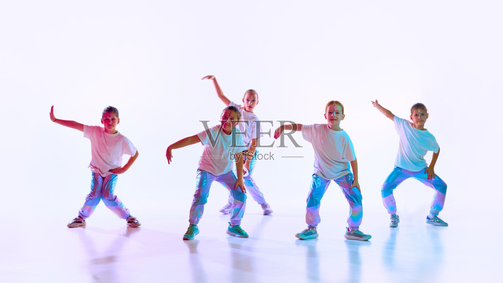 一群女孩穿着运动风格的衣服，搭配时髦的创意发型，在霓虹灯的渐变背景下跳舞同步编舞课。照片摄影图片