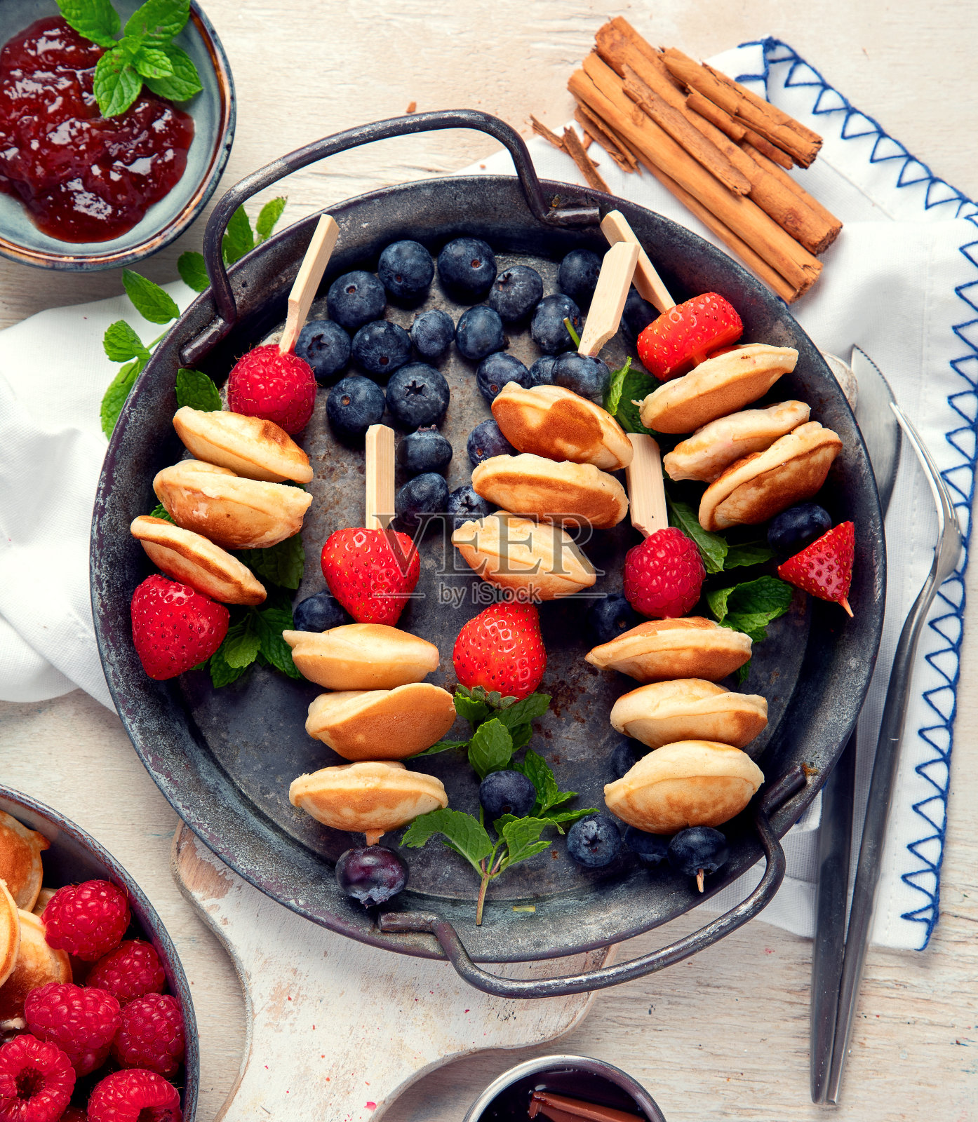 美味的蓝莓，草莓和覆盆子煎饼。甜美可口的早餐在浅色的背景照片摄影图片