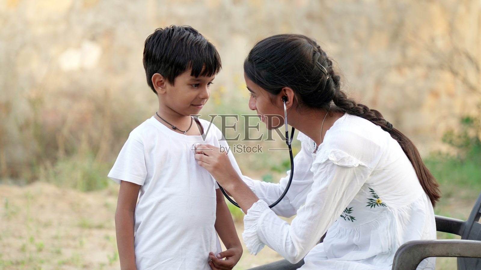 女医生或儿科医生在诊所用听诊器听男孩病人的心跳。照片摄影图片