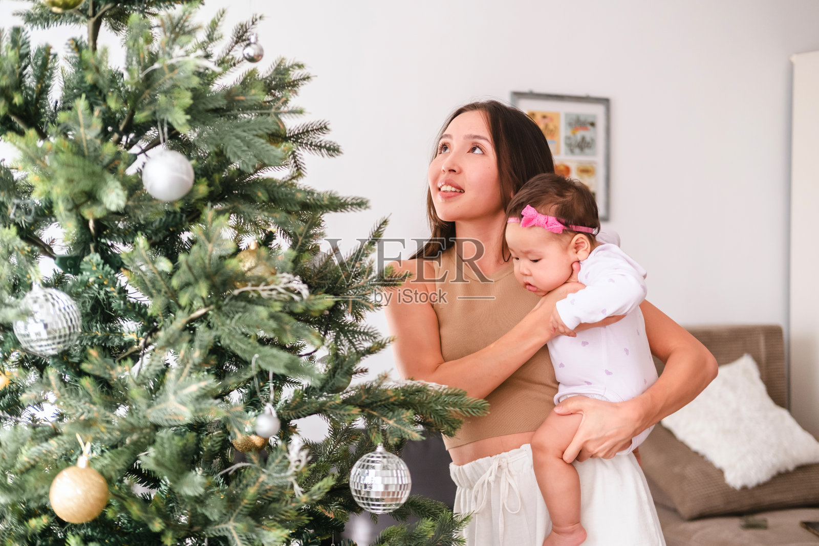 年轻的亚洲母亲和可爱的小女儿一起在家里装饰圣诞树。圣诞生活方式主题。庆祝圣诞节。照片摄影图片