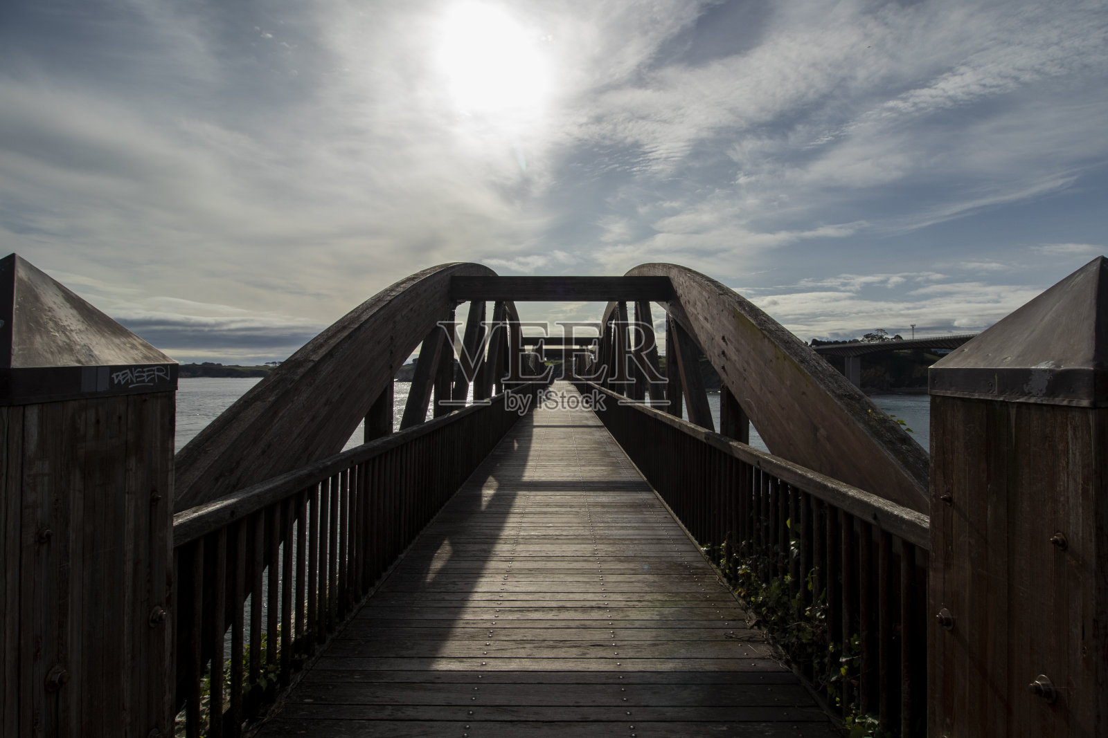 阳光下的木桥，平静的水面反射着蓝天照片摄影图片