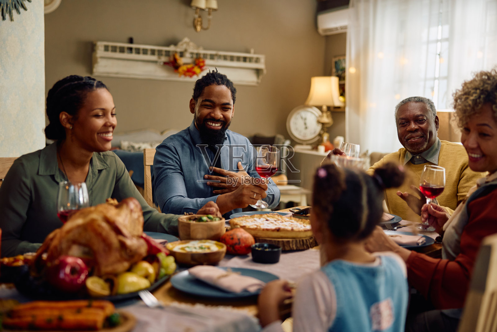 快乐的黑人大家庭在餐桌上谈论感恩节大餐。照片摄影图片