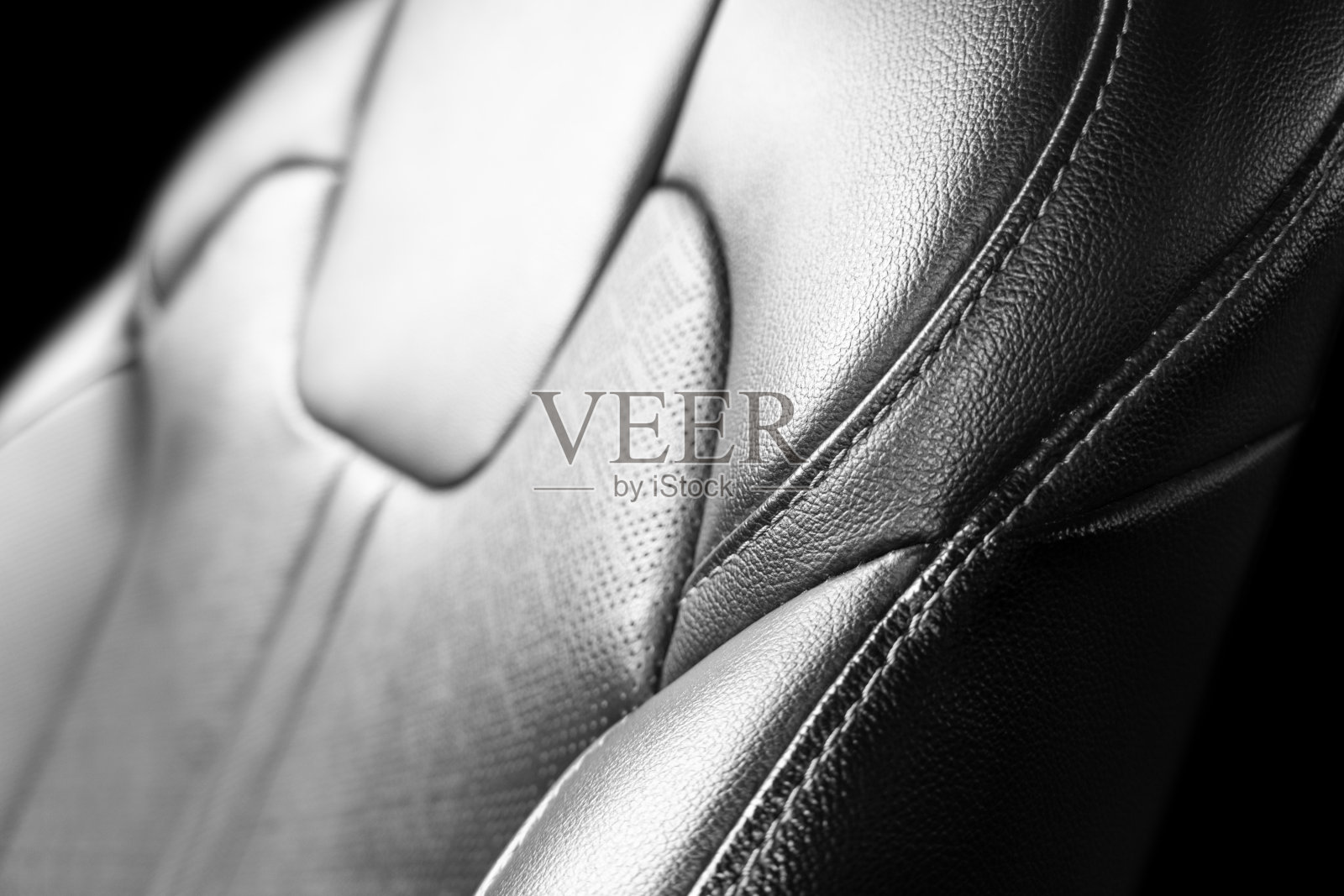 汽车黑色皮革内饰。部分黑色皮革汽车座椅细节与白色拼接。名车内饰。穿孔真皮座椅隔离。穿孔皮革。照片摄影图片