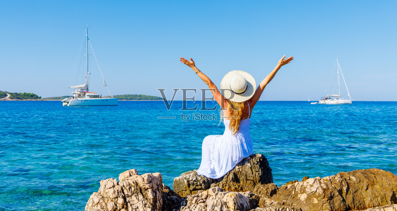 旅游目的地，暑假，游轮概念——快乐的女人穿着白色的裙子，张开双臂享受大海和帆船游艇(克罗地亚达尔马提亚)照片摄影图片