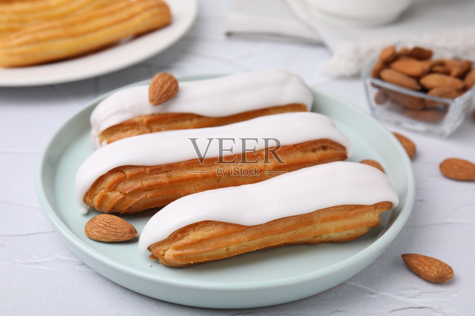 白色有质感的桌子上，美味的泡芙上覆盖着釉料和杏仁，特写照片摄影图片