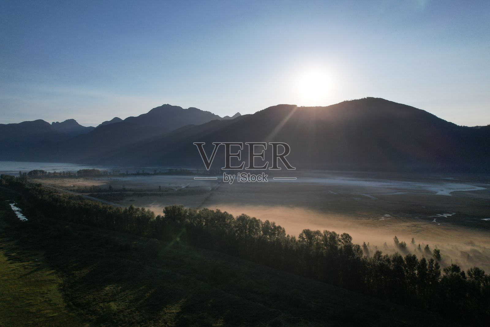 在一个阳光明媚的日子里，鸟瞰一个被群山环绕的宁静湖泊照片摄影图片