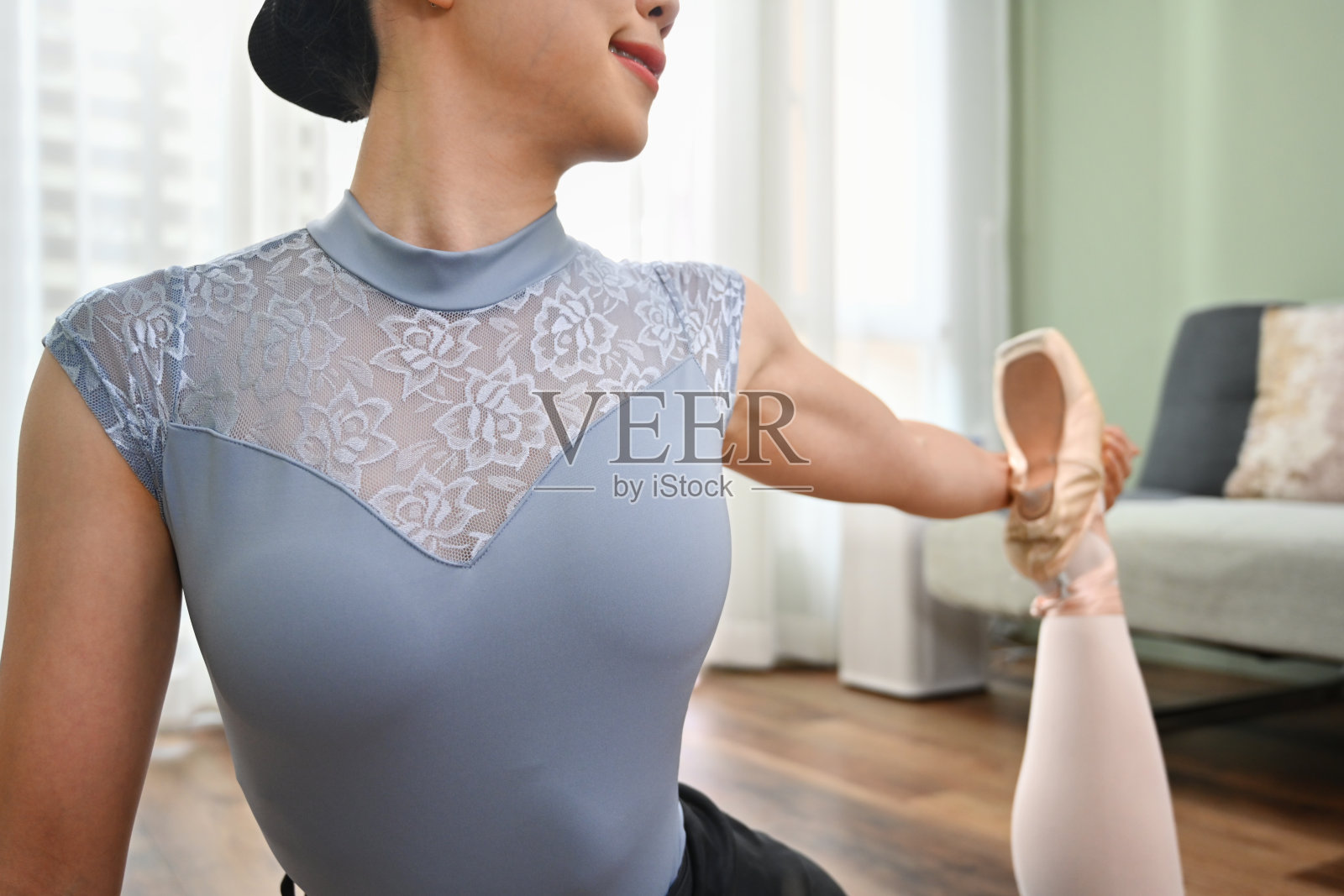 年轻女子穿着足尖鞋坐在地板上热身，然后在家练习芭蕾舞照片摄影图片