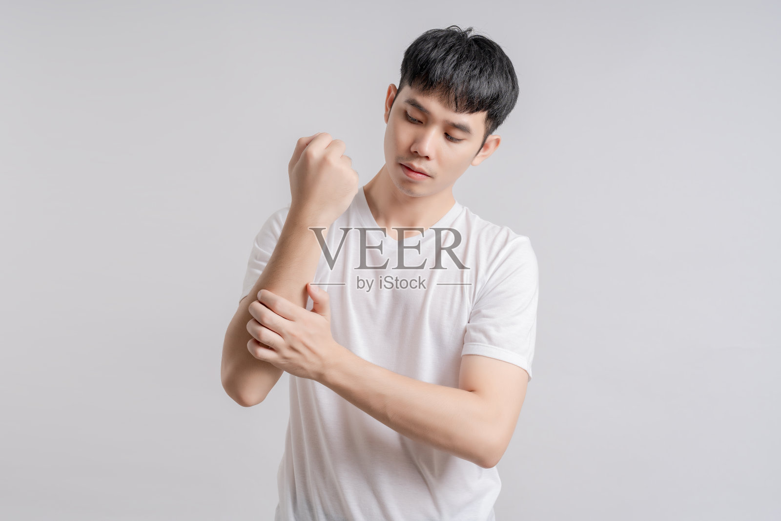 英俊的年轻人脸上带着痛苦的表情，因为受伤而抱着手臂。照片摄影图片