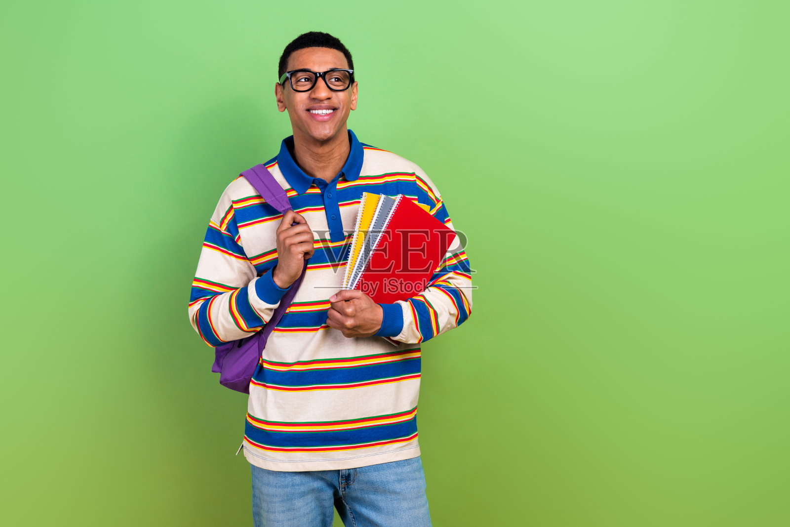 照片肖像中有魅力的年轻人手持手册，看起来空无一人，穿着时髦的条纹衣服，孤立在绿色的背景上照片摄影图片