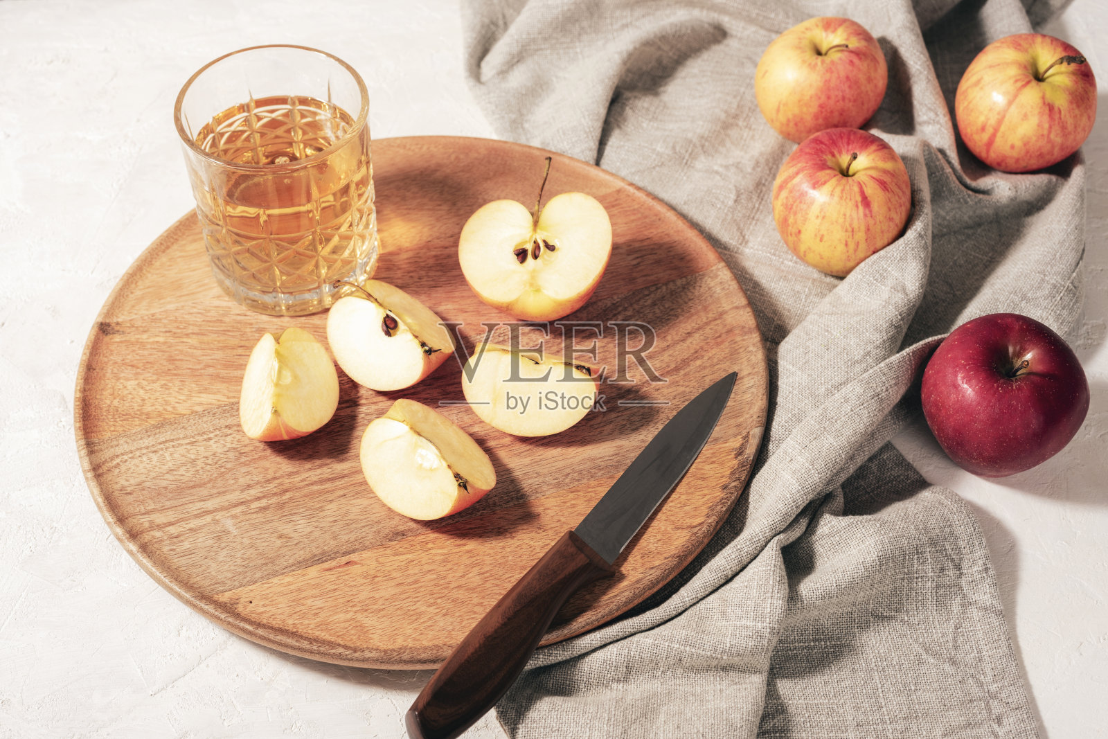 新鲜成熟的苹果和苹果汁放在木托盘上的玻璃杯里，白色的桌子上放着灰色的餐巾。秋收，感恩观念。俯视图照片摄影图片