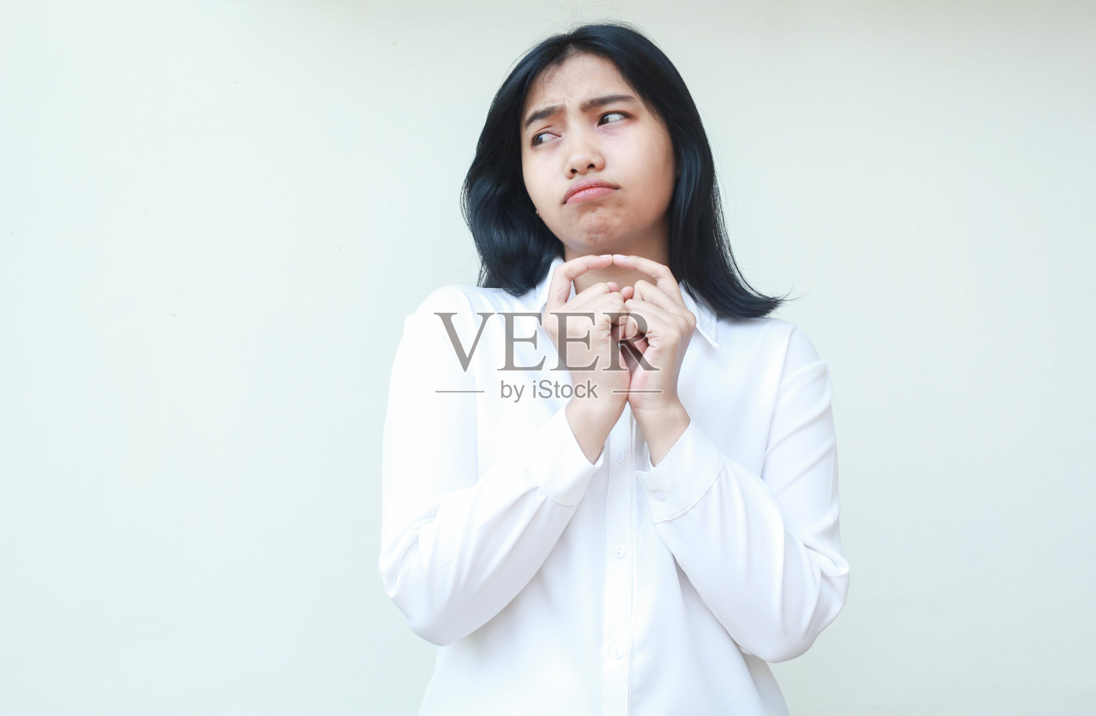 体贴可爱的亚洲女商人一起伸出食指，露出悲伤要求的表情，望向空旷的地方，穿着白衬衫正装，加班的沮丧，孤立地站着照片摄影图片