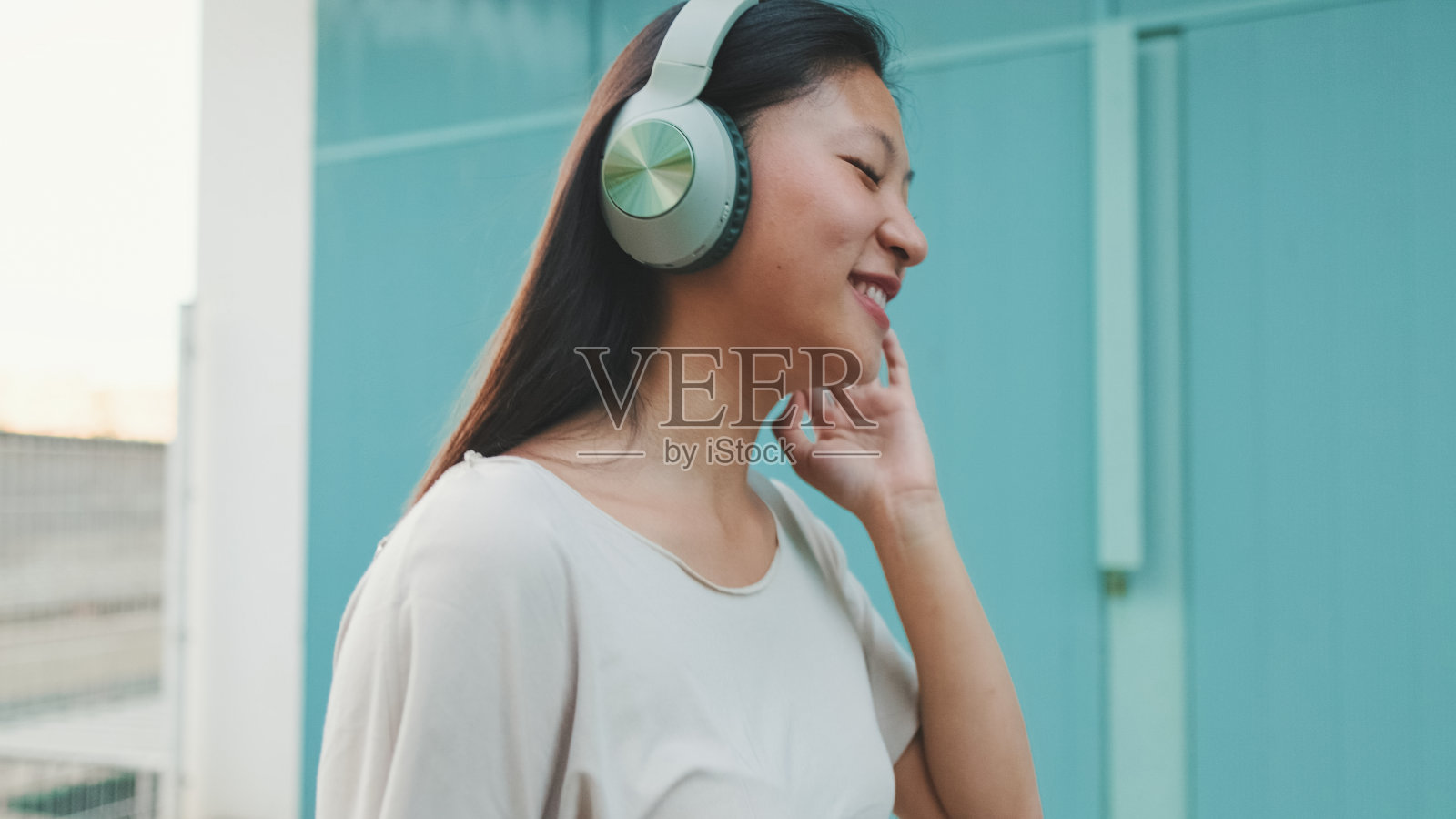 快乐美丽的黑发女孩戴着耳机，穿着休闲服，听着音乐和唱歌照片摄影图片