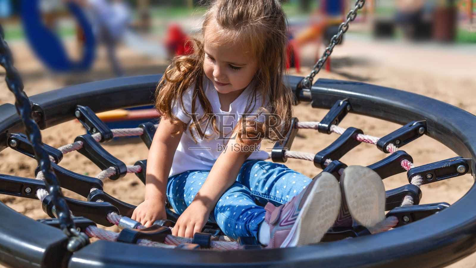 秋天的一天，一个小女孩在公园的操场上荡秋千。快乐的孩子喜欢荡秋千。儿童户外活动休闲。照片摄影图片