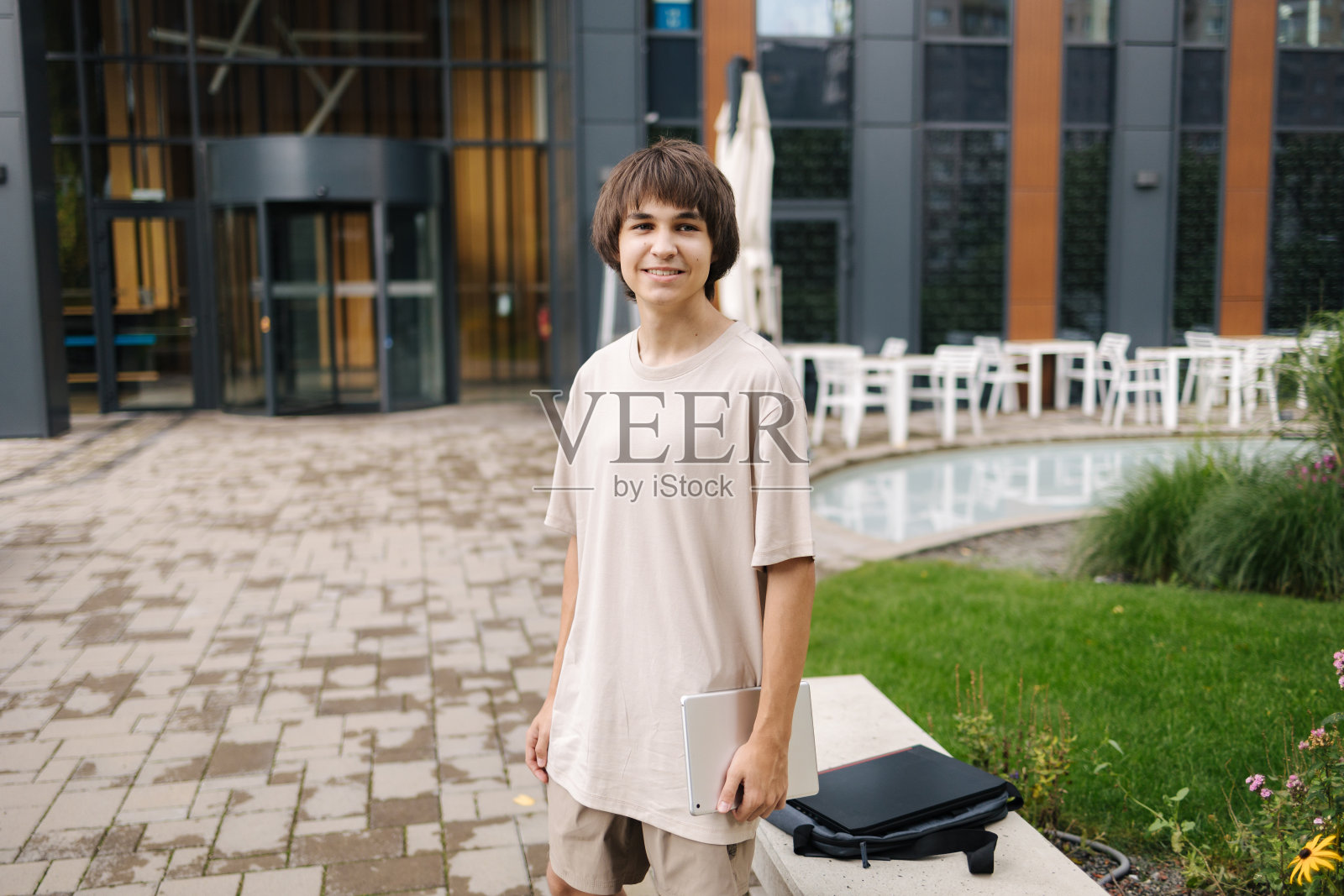 快乐的少年在户外使用平板电脑后回家照片摄影图片