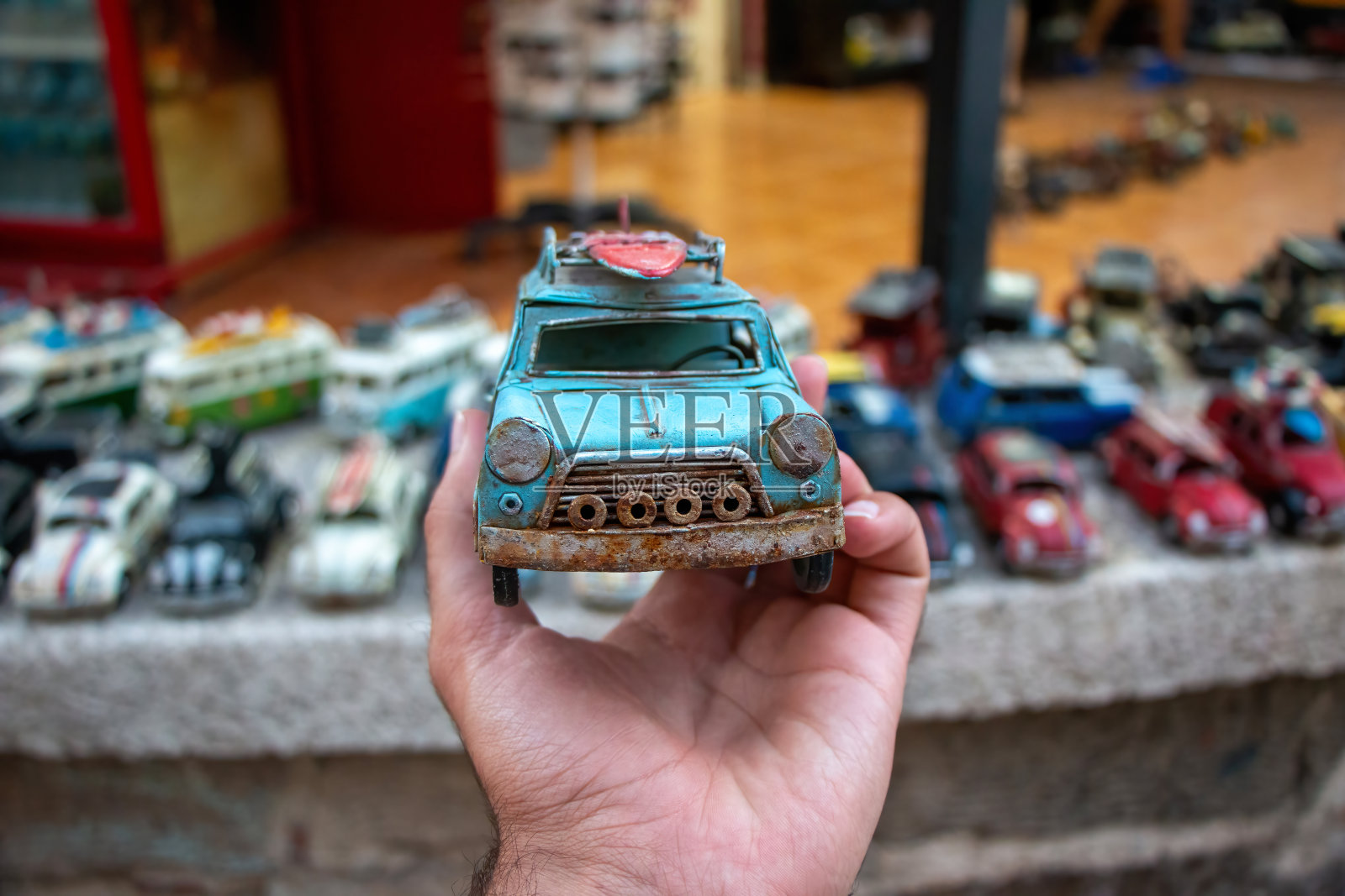 大众甲壳虫在一家出售玩具汽车模型的商店里。男人手里拿着汽车。旧型号的蓝色汽车模型。老旧的复古车。照片摄影图片