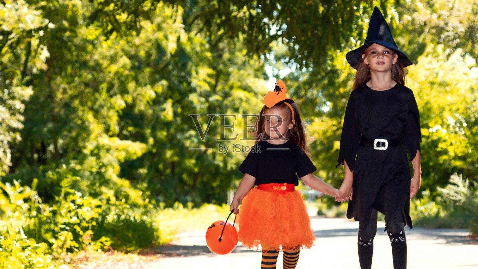 孩子们穿着万圣节服装不给糖就捣蛋。万圣节的庆祝活动。两个跑着的孩子拿着篮子装糖果照片摄影图片