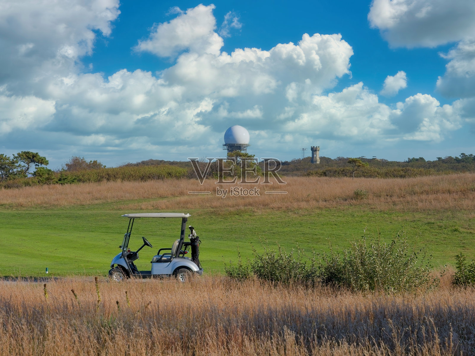 美国联邦航空局和国防部联合监视雷达ARSR-4前的高尔夫球场果岭和高尔夫球车照片摄影图片