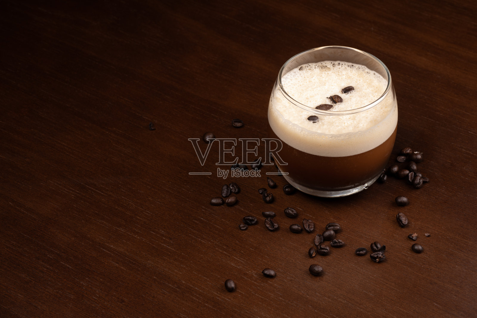 Carajillo在木桌上喝浓缩咖啡和利口酒，角落里放着烤过的咖啡豆照片摄影图片