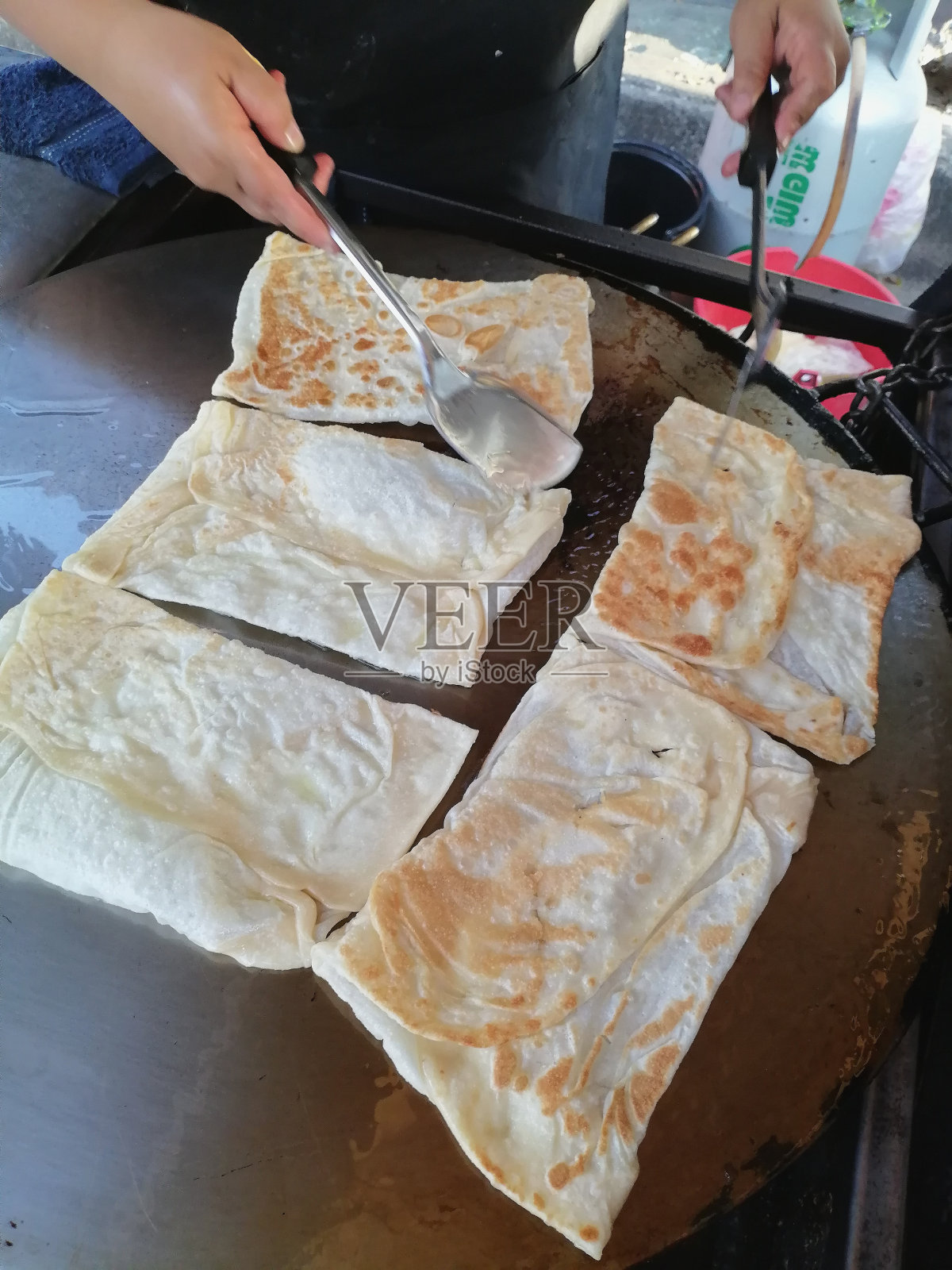 一名妇女正在做印度烤饼，这是街头小吃照片摄影图片