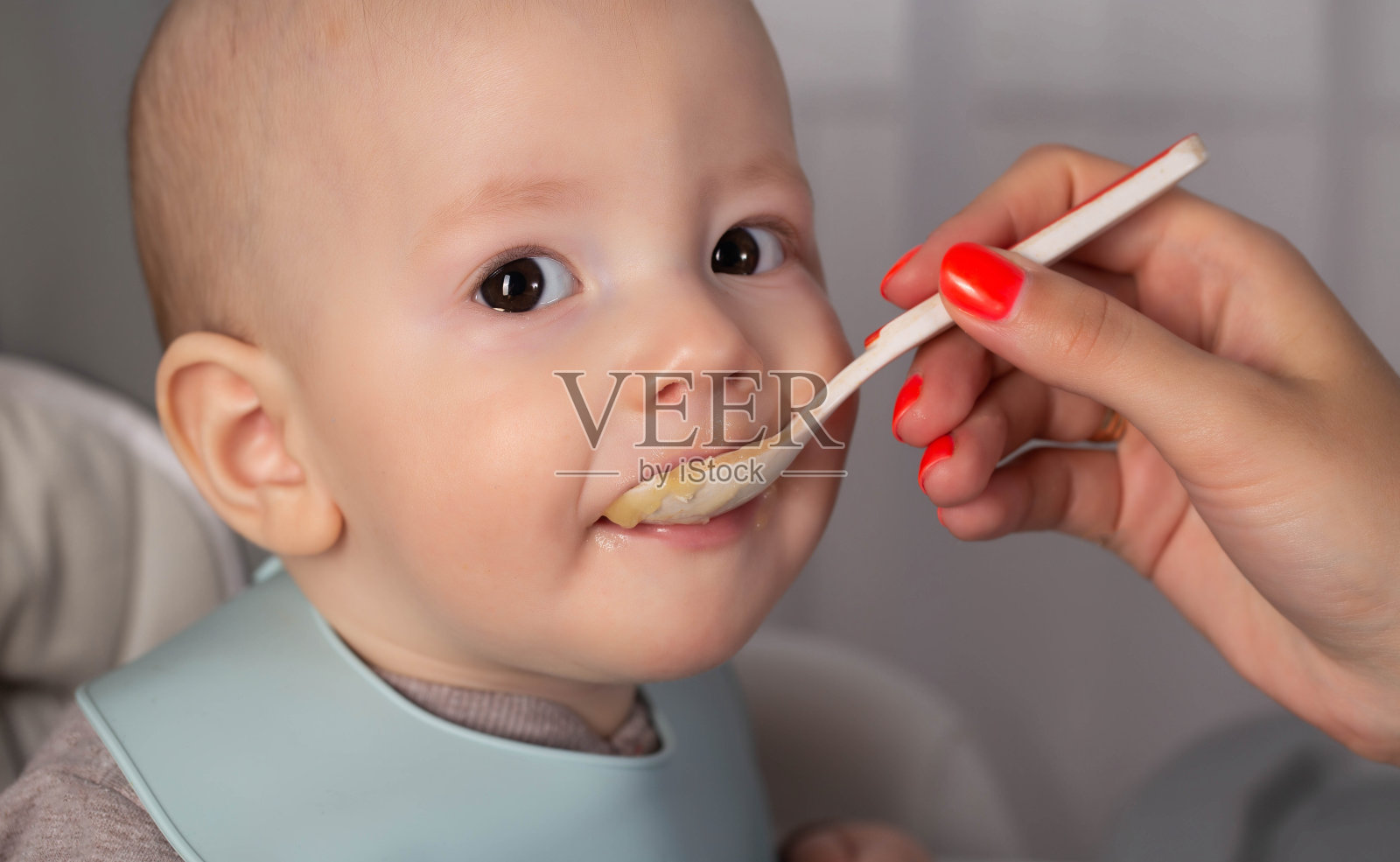 妈妈用勺子喂小男孩蔬菜泥。喂养7个月大的孩子。特写镜头照片摄影图片