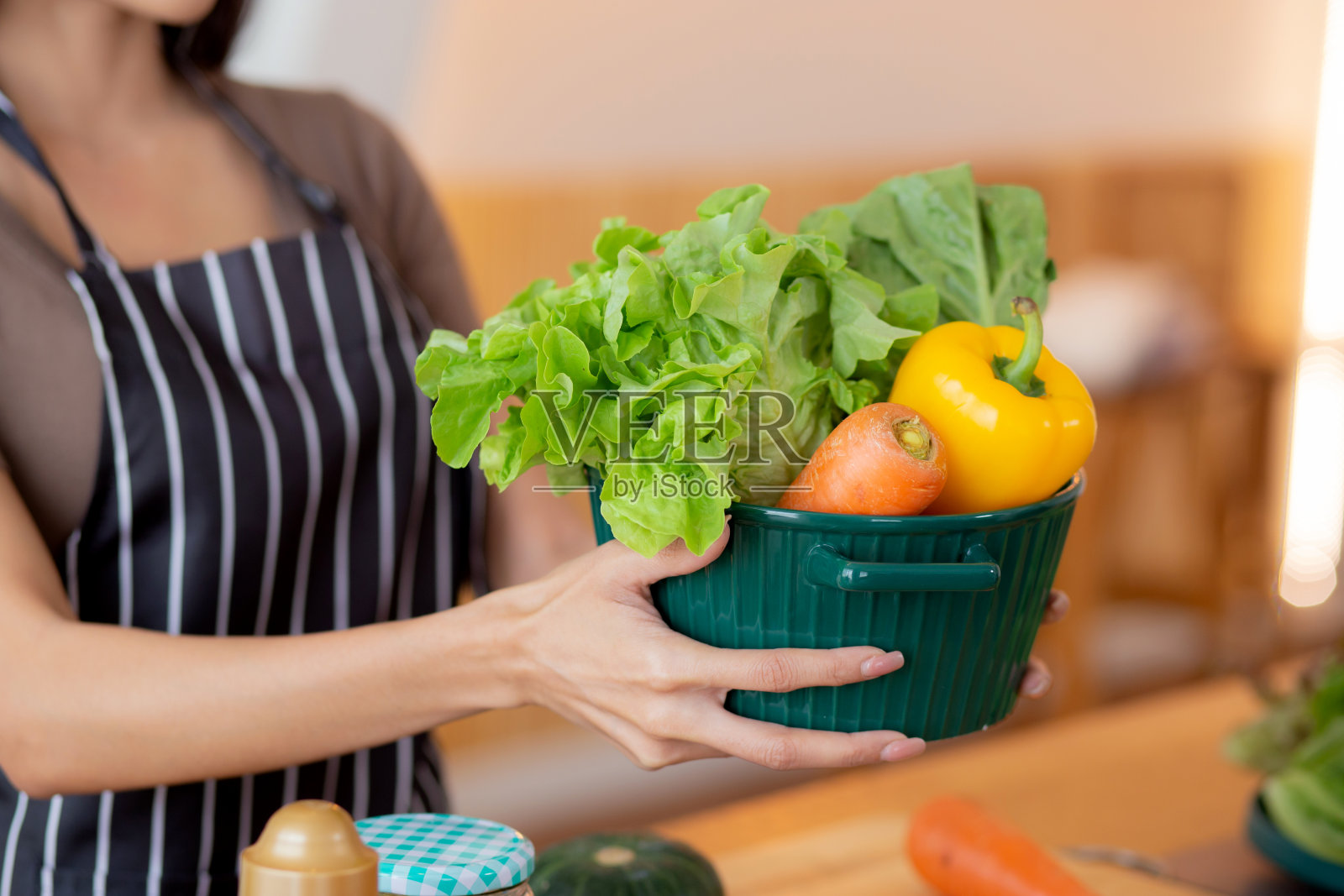 特写:年轻的亚洲妇女在家里的厨房里拿着菜篮准备烹饪沙拉蔬菜食品，妇女站着提着新鲜的菜篮，生活方式的概念。照片摄影图片