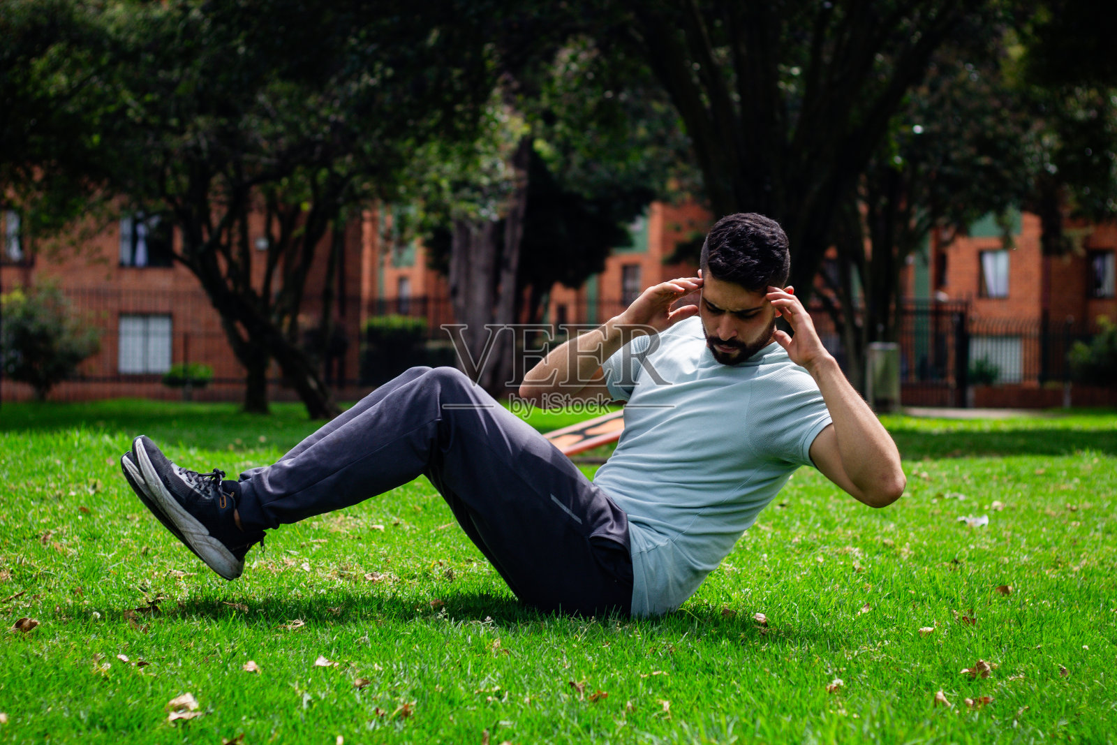 年轻的健身男子在城市的一个公园里做腹部运动照片摄影图片