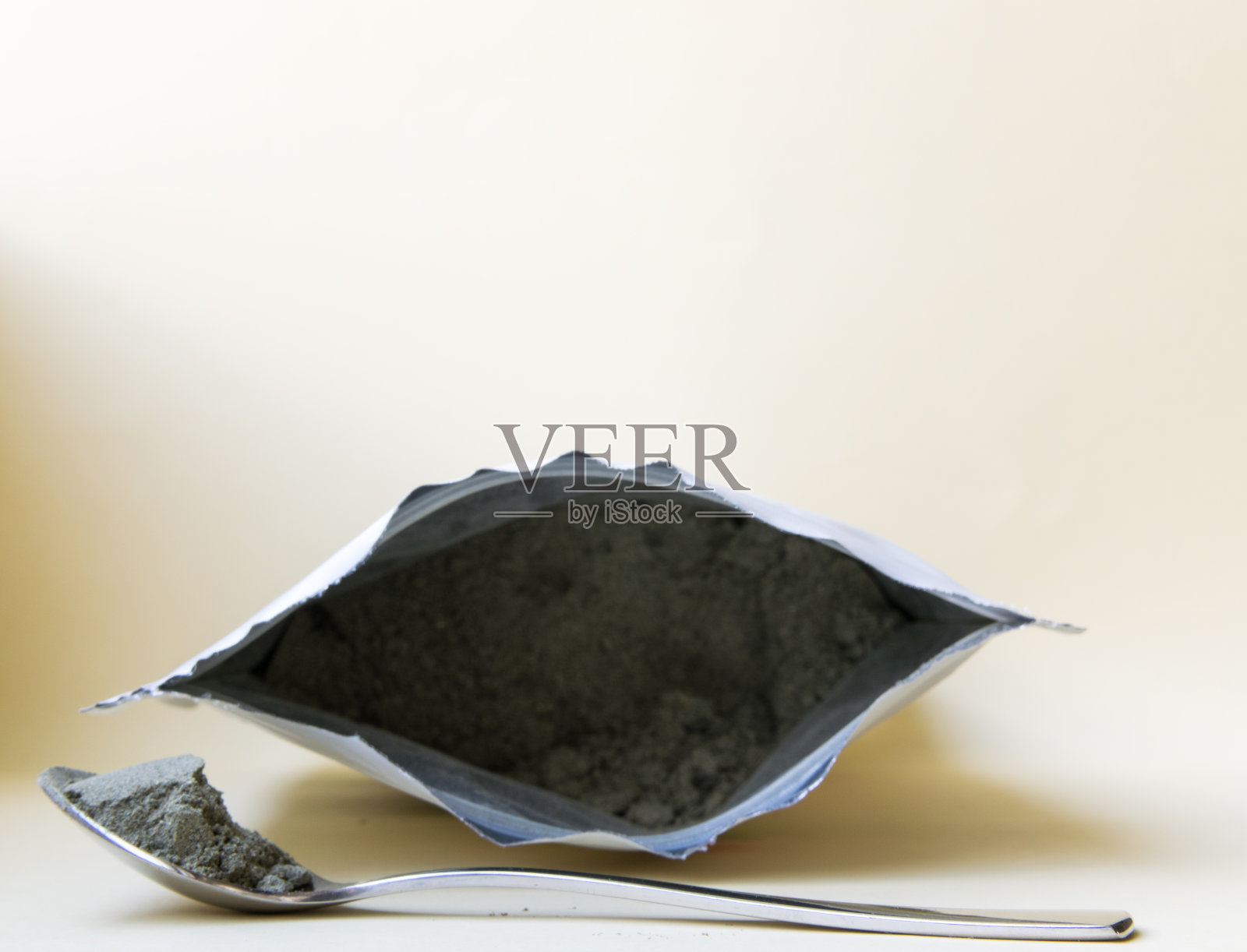 用勺子靠近有粉末的包装。照片摄影图片