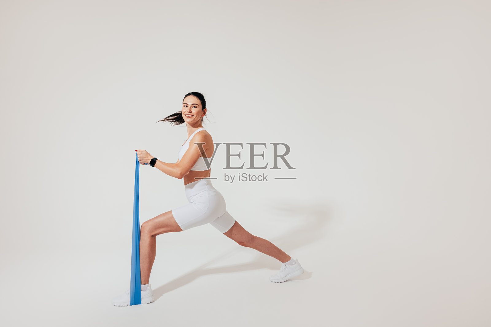 身穿白色健身服的年轻苗条女性在录音室里练习抵抗乐队照片摄影图片