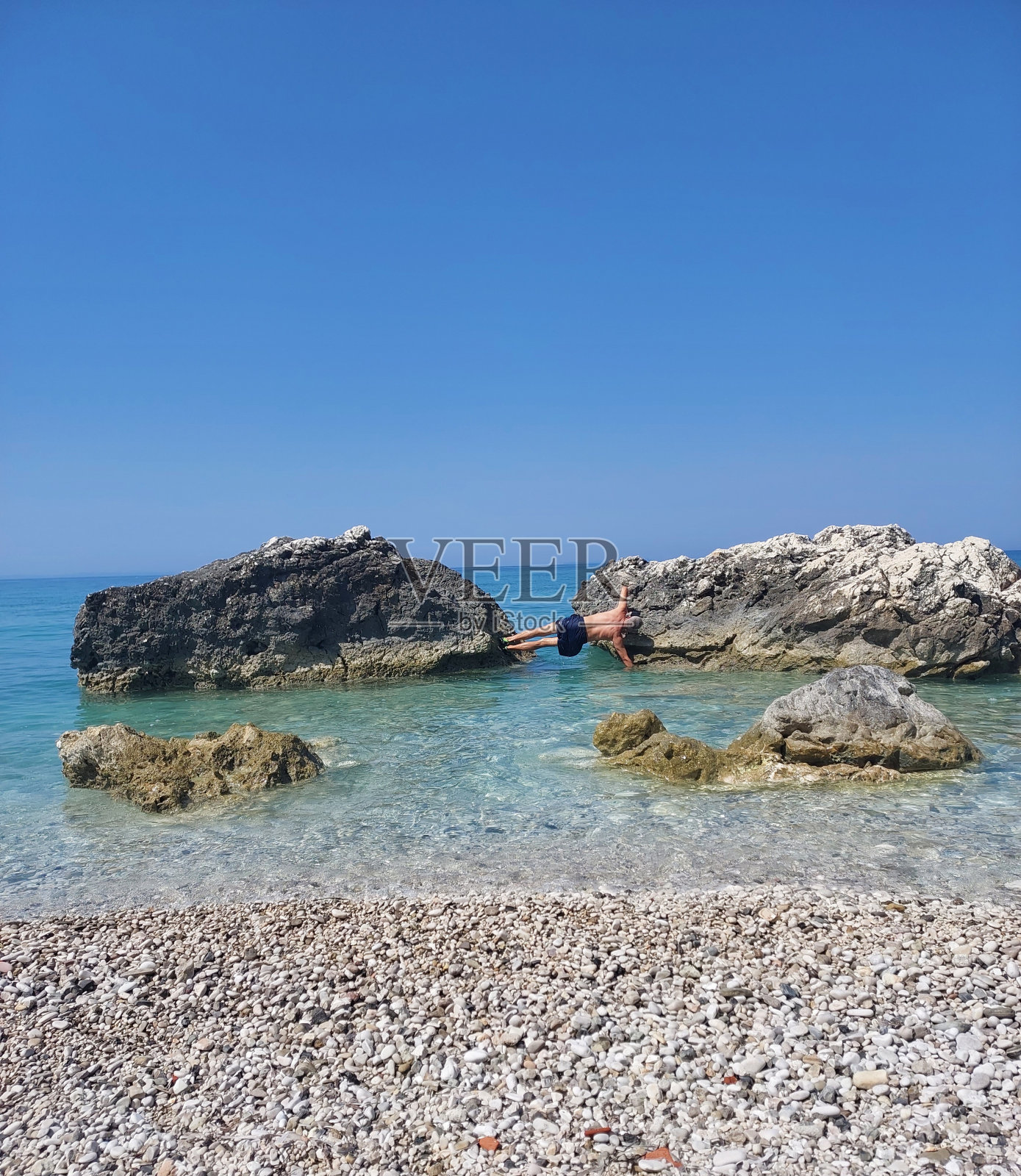 一名男子在美丽的大海中，在强大的石头中展示身体健康照片摄影图片