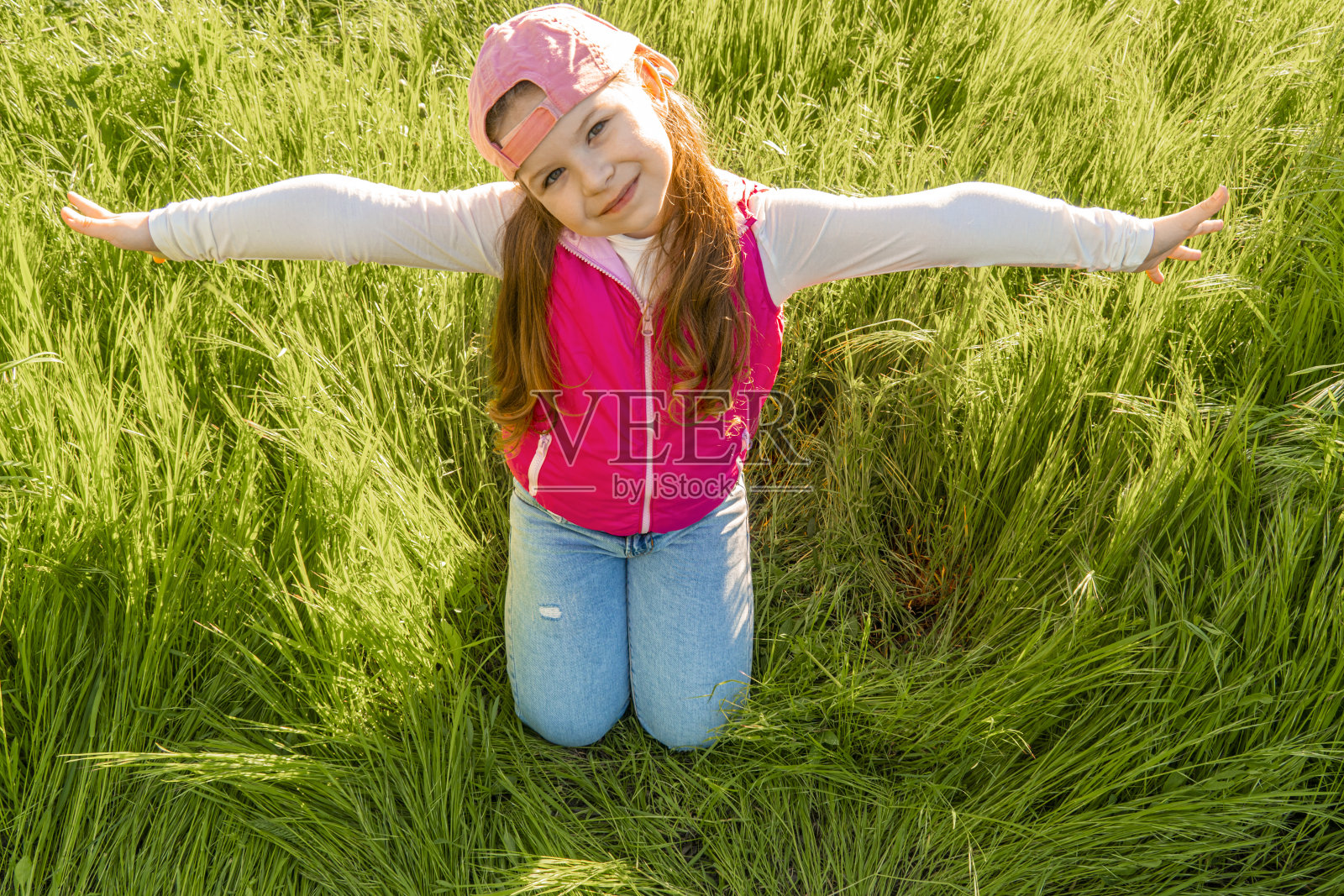 快乐的小女孩坐在茂密的草地上照片摄影图片