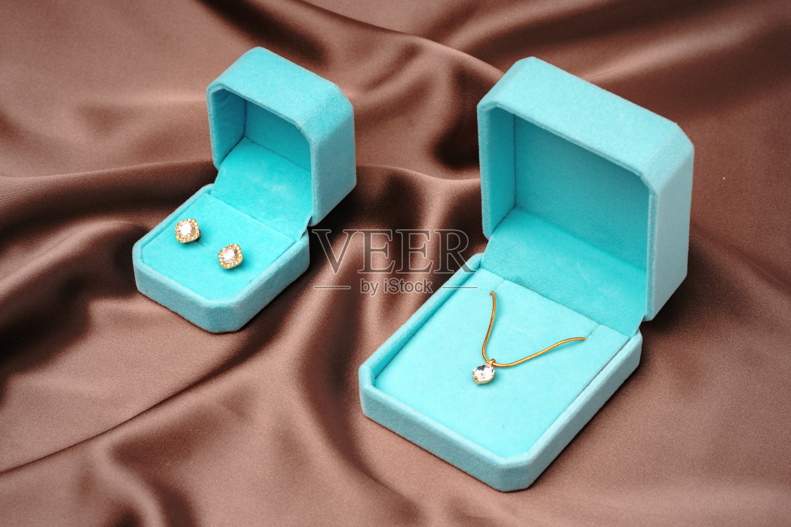 金色项链和耳环在棕色丝绸背景蓝色首饰盒照片摄影图片