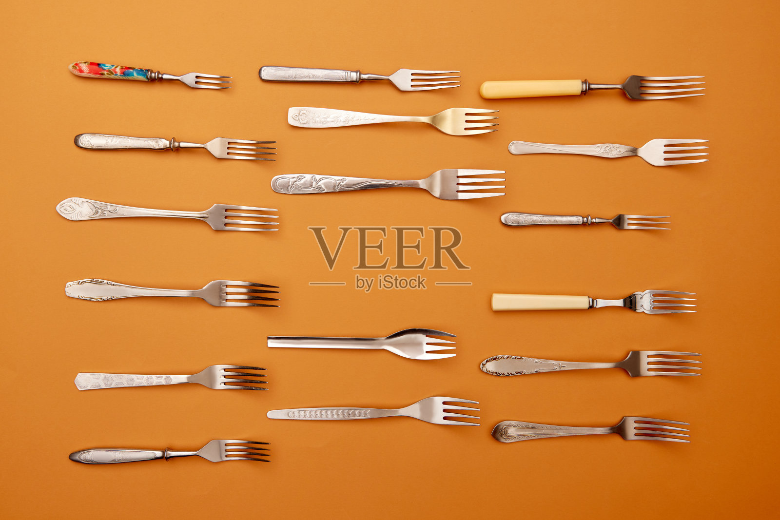 餐具。顶视图平面照片的各种不锈钢，古董银器和金叉安排在橙色工作室的背景。照片摄影图片