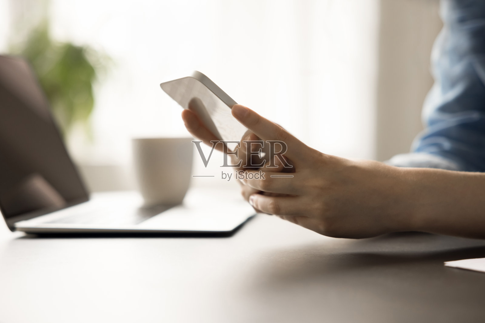 白女士手里的手机放在工作桌上照片摄影图片