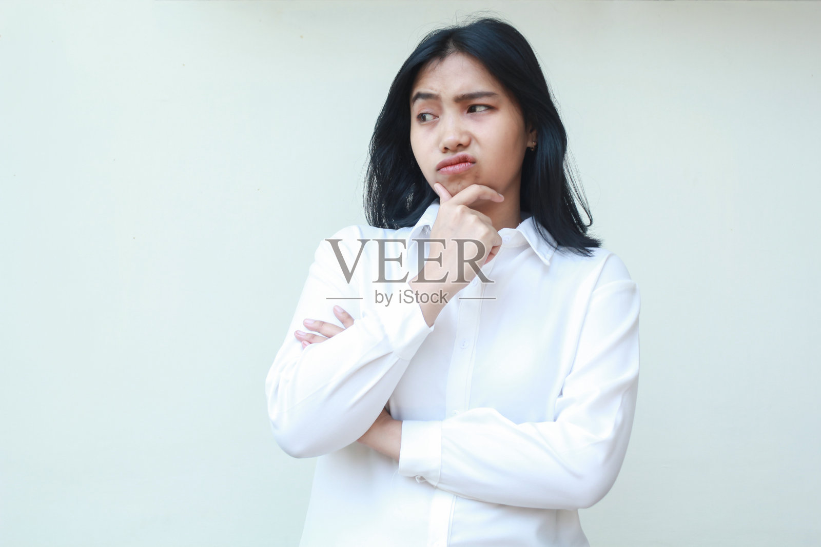 沉思的亚洲年轻女商人的形象思考她的问题，双手放在下巴上，双臂交叉，关注地看着别处，思考着恐惧的表情，站着照片摄影图片
