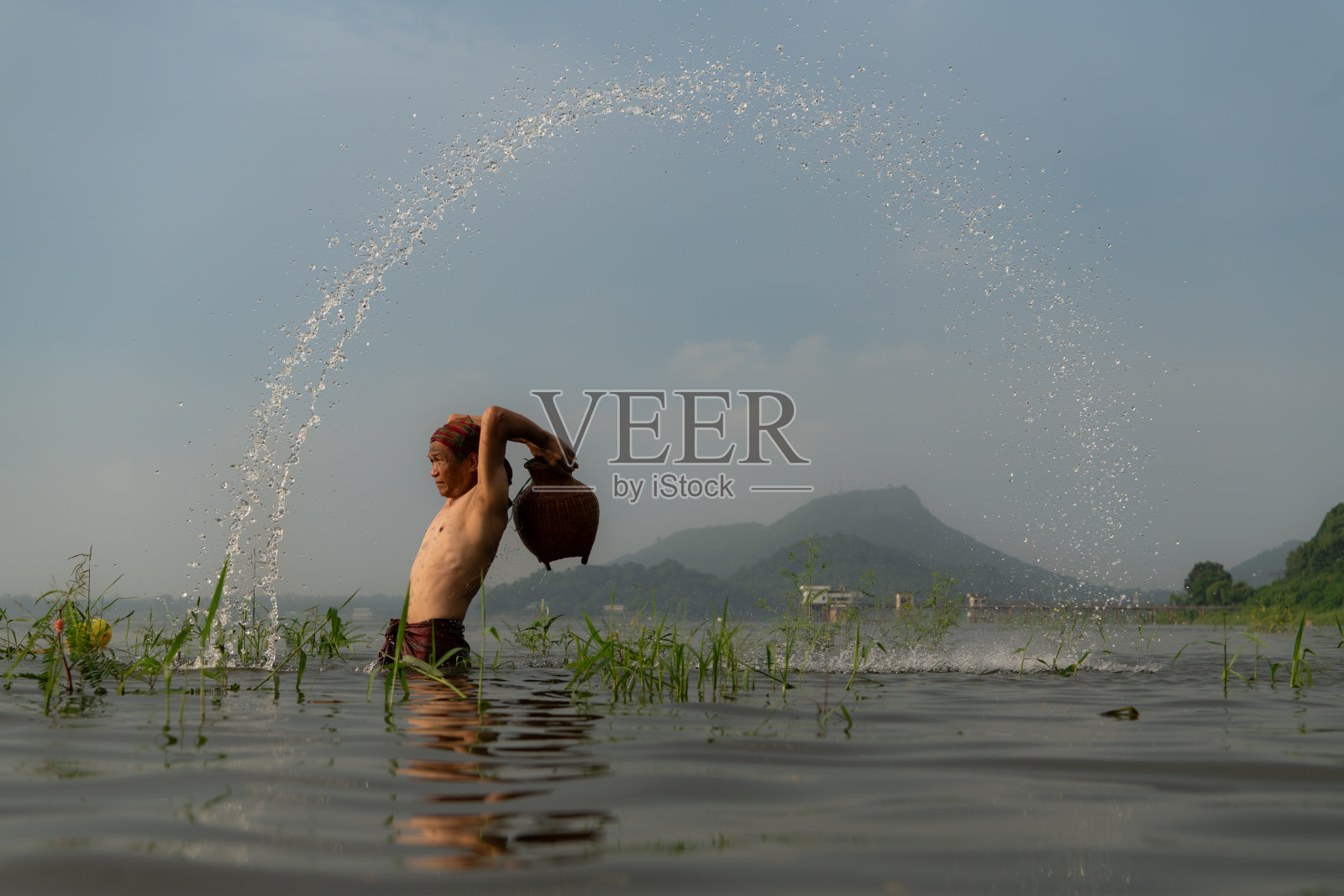 渔民使用传统的捕鱼设备捕鱼后，清理和在水里玩耍。照片摄影图片