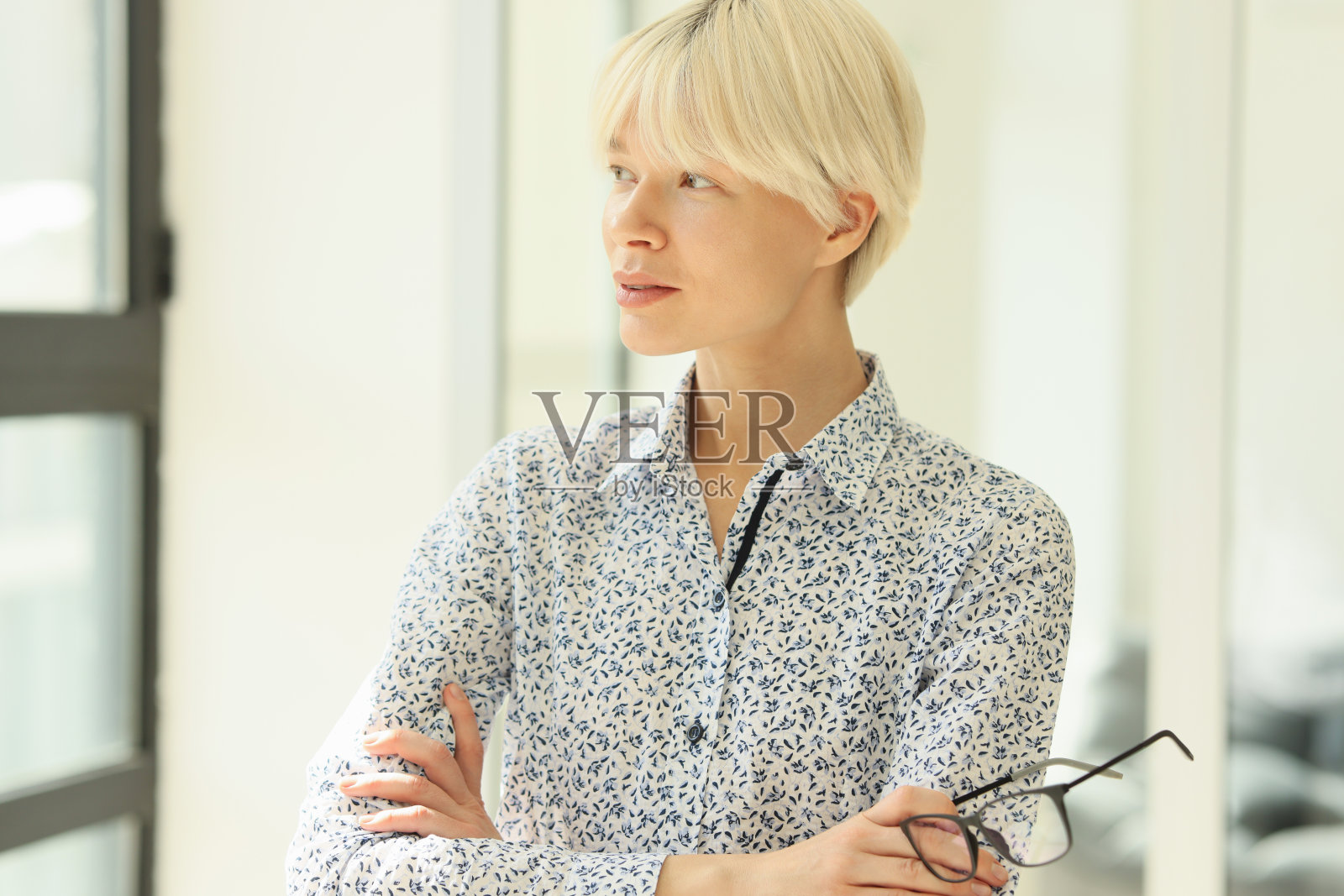 沉思的金发女人抱着双臂在窗边做梦照片摄影图片